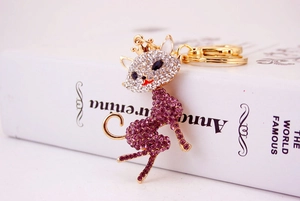 Detail of a golden cat keychain with purple crystals resting on a classic book spine