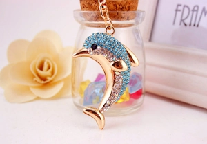 Macro view of gold dolphin keychain with blue and white rhinestones on a floral background