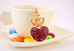 Detailed shot of a purple rhinestone heart keychain with crown on a white cup