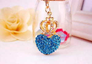 Close-up of golden crown heart keychain with blue crystals and sparkling metal details