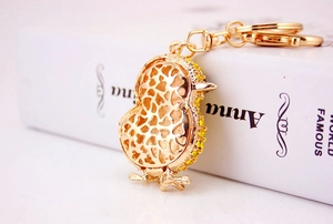 Detail of golden chick keychain featuring yellow crystals and hollow heart pattern
