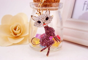Detailed view of fox keychain with purple and white crystals on polished gold metal