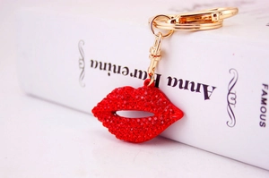 Close-up of red rhinestone lips keychain with golden lobster clasp on book background