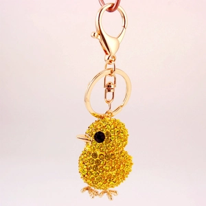 Golden yellow chick keychain with sparkling crystals on a soft pink background