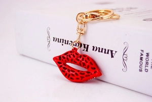 Detail of red leopard print lip keychain with gold lobster clasp on white book