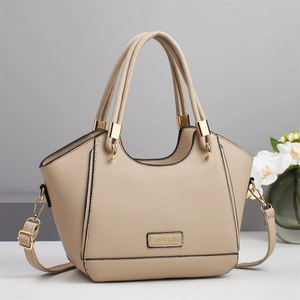 Dettaglio della pelle a grana e logo in metallo dorato sulla borsa a mano beige