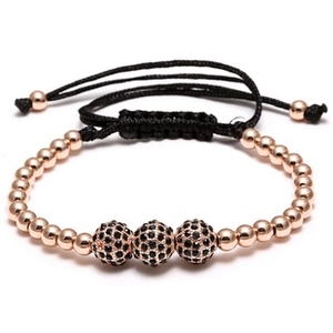 Detail of woven bracelet with rose gold beads and three black rhinestone charms