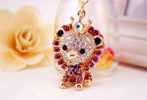 Macro shot of a golden lion keychain with purple and clear rhinestones and a crown