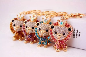 Detail of four colorful rhinestone lion keychains with golden metal crowns on white book