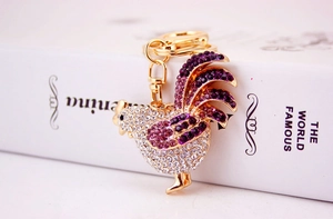 Macro shot of golden rooster keychain with sparkling purple and clear rhinestones