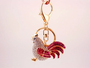 Macro view of rooster keychain with sparkling white and red rhinestones on gold metal
