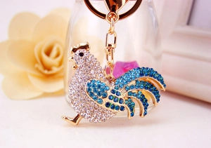 Close-up of golden rooster keychain with sparkling blue and silver rhinestones detail
