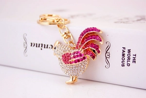 Detail of a sparkling rooster keychain with pink rhinestones and a lobster clasp