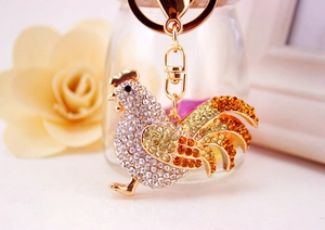Macro shot of sparkling rhinestone rooster keychain with golden metal clasp and ring