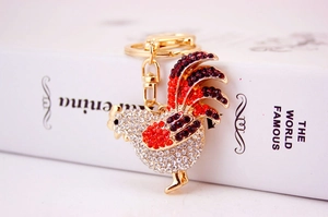 Detailed close-up of a golden rooster keychain featuring sparkling red and white rhinestones