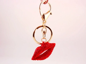 Detail of red rhinestone lips keychain with golden spring buckle on a pink background