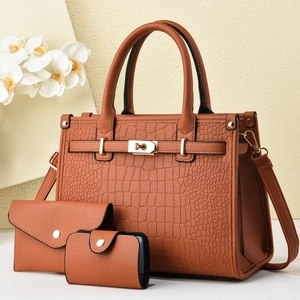 Detail of tan crocodile embossed leather tote bag with gold twist lock and texture