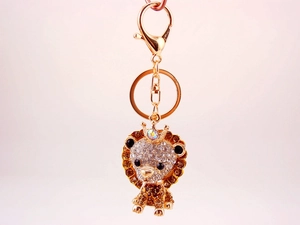 Detail of a golden lion keychain with sparkling crystals and a crown on soft background
