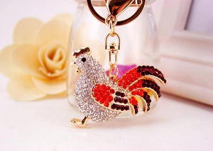 Detailed close-up of a golden rooster keychain encrusted with sparkling red crystals