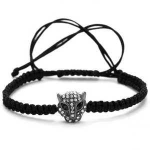 Macro detail of black braided bracelet featuring a silver leopard head with crystals