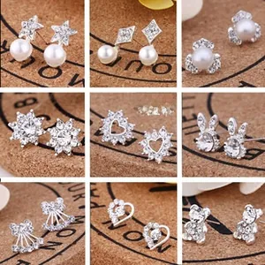 Set of nine silver alloy stud earrings with pearls and crystals on cork display board