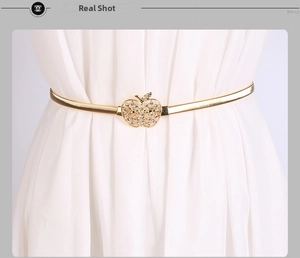 Détail de la ceinture élastique dorée avec boucle pomme en strass sur une robe chic