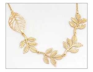 Detailed close-up of golden leaf-shaped hair clip with intricate vein textures on white background