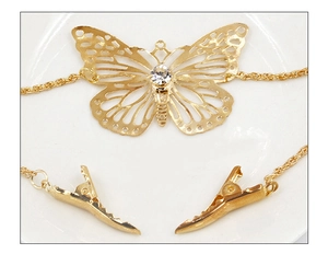 Close-up of golden hollow butterfly hair clip with crystal inlay and metal chain tassels