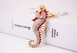 Macro detail of golden seahorse keychain with sparkling rhinestones and red enamel finish
