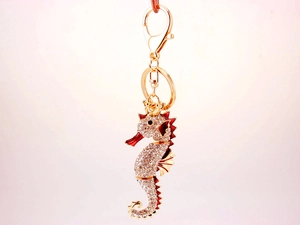 Detail of a golden seahorse keychain with sparkling rhinestones and red enamel accents