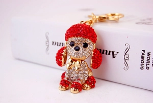 Close-up of golden dog keychain with red and clear rhinestones and bow detail