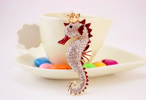Close-up of golden seahorse keychain with sparkling crystals and red enamel accents