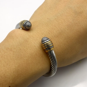 Twisted cable cuff bracelet in two-tone silver and gold steel worn on the wrist