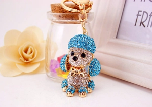 Detail of creative dog keychain featuring blue and white crystals on a gold metal frame