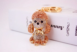 Close-up of a golden poodle keychain with amber crystals against a soft background