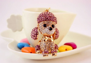 Detailed close-up of a poodle keychain with purple and clear rhinestones on gold metal