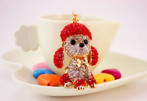 Detailed view of a sparkling crystal-encrusted red teddy dog keychain on a heart-shaped tray