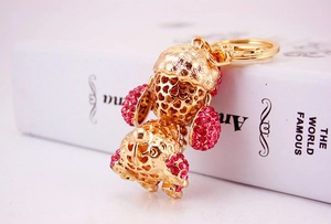 Detail of golden puppy keychain with pink crystals on a book background