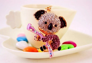 Close-up of golden koala keychain featuring sparkling clear and pink-purple rhinestones