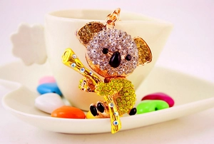 Detailed view of gold koala keychain with rhinestones holding bamboo on a heart dish