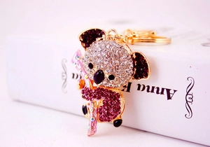 Close-up of a sparkling koala keychain with white and pink rhinestones on a golden base