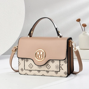 Elegant two-tone crossbody bag with gold M buckle and monogram texture on white background