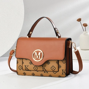 Close-up of brown and beige crossbody bag with gold M logo and floral print details