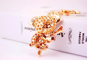 Detail of a golden koala keychain with hollow design placed on a white book surface