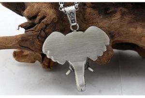 Macro shot of silver elephant pendant back with brushed texture on wood base