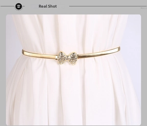 Détail d'une fine chaîne de taille dorée élastique avec boucle en nœud strass brillant