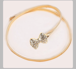 Vue détaillée d'une ceinture dorée à ressort avec une boucle nœud en strass étincelante