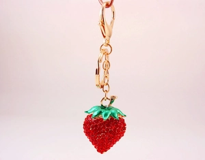 Close-up of sparkling rhinestone strawberry keychain with gold lobster clasp and ring