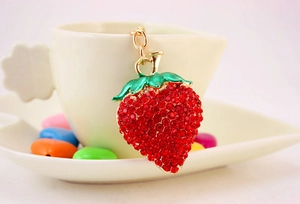Close-up of sparkling red and green rhinestone strawberry keychain with gold chain