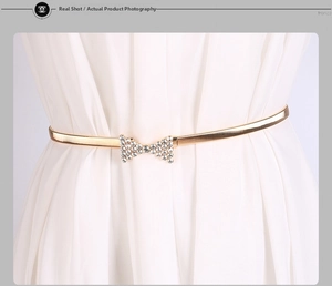 Détail de la ceinture extensible dorée avec une boucle nœud sertie de strass brillants